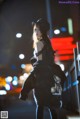 A woman in a black dress and hat is walking down the street.