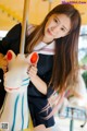 A woman in a school uniform holding a toy horse.