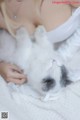 A woman laying on top of a white blanket holding a cat.