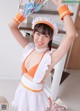 A woman in an orange and white maid outfit holding a broom.