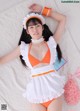 A woman in an orange and white maid outfit laying on a white rug.