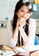 A young woman sitting at a desk with a pencil in her hand.