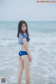 A woman in a blue bikini standing in the ocean.