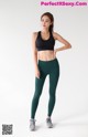 a woman in a black sports bra top and green leggings