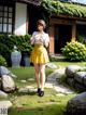 A woman in a yellow skirt standing in front of a house.