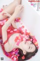 A woman laying in a bathtub covered in rose petals.