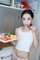 A woman holding a plate of food in a kitchen.