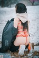 A woman in a bikini sitting in the snow.