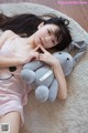 A woman laying on the floor with a stuffed animal.