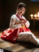 A woman in a red and white hanbok sitting on the floor.