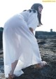 A woman in a white dress standing on a rock.