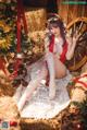 A woman in a red bathing suit sitting on hay next to a Christmas tree.