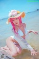 A woman in a white bikini and a straw hat on the beach.