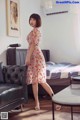 A woman in a floral dress standing in a living room.