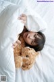 A little girl laying in bed with a teddy bear.