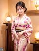 A woman in a pink kimono posing for a picture.