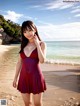 A woman in a red dress standing on a beach.