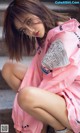 A woman in a pink raincoat sitting on some steps.