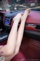 A woman's legs are sitting in the driver's seat of a car.