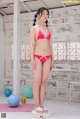 A woman in a red bikini standing on a scale.