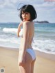 A woman in a white bikini standing on a beach.