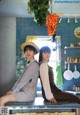 A couple of women sitting on top of a kitchen counter.