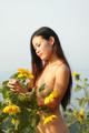 A naked woman standing in a field of sunflowers.