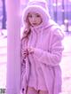 A woman in a pink hooded jacket leaning against a pole.