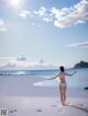 A woman in a white bikini standing on a beach.